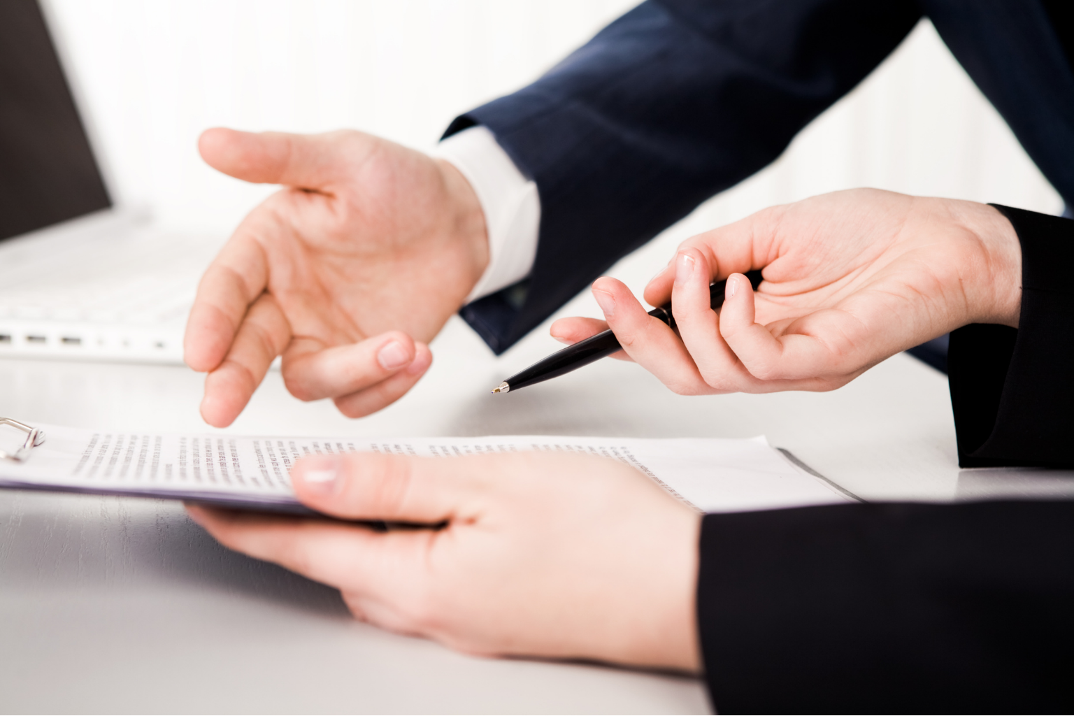 Hände zweier Personen, die augenscheinlich miteinander sprechen und gestikulieren über einem Blatt Papier